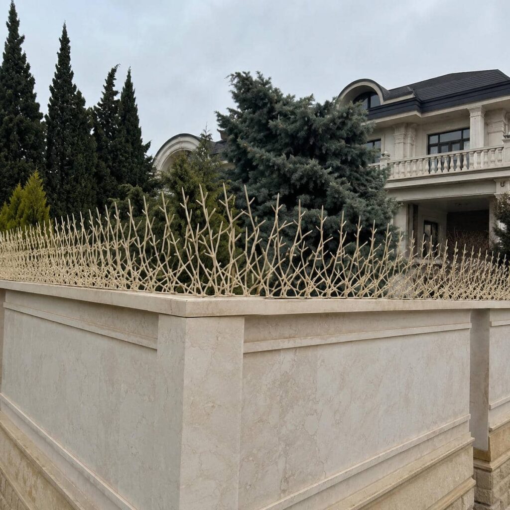 نرده سرنیزه ای مشکی روی دیوار سنگی ویلا