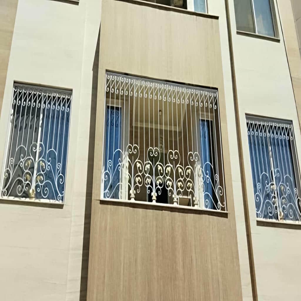 نرده فلزی مشکی روی دیوار سنگی نیمه‌تمام